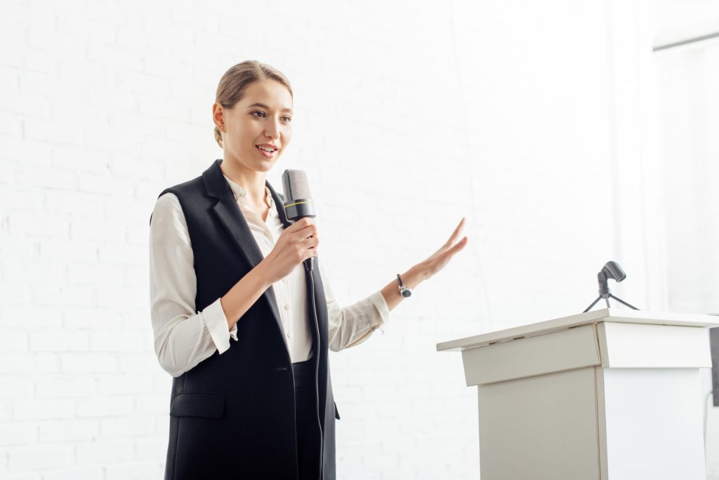attractive businesswoman holding microphone and talking during conference in conference hall